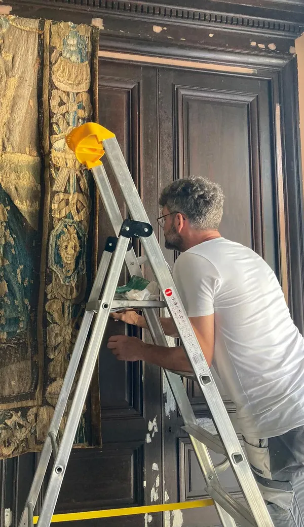Schilder André Slijkhuis op een ladder bij een donkere monumentale deur